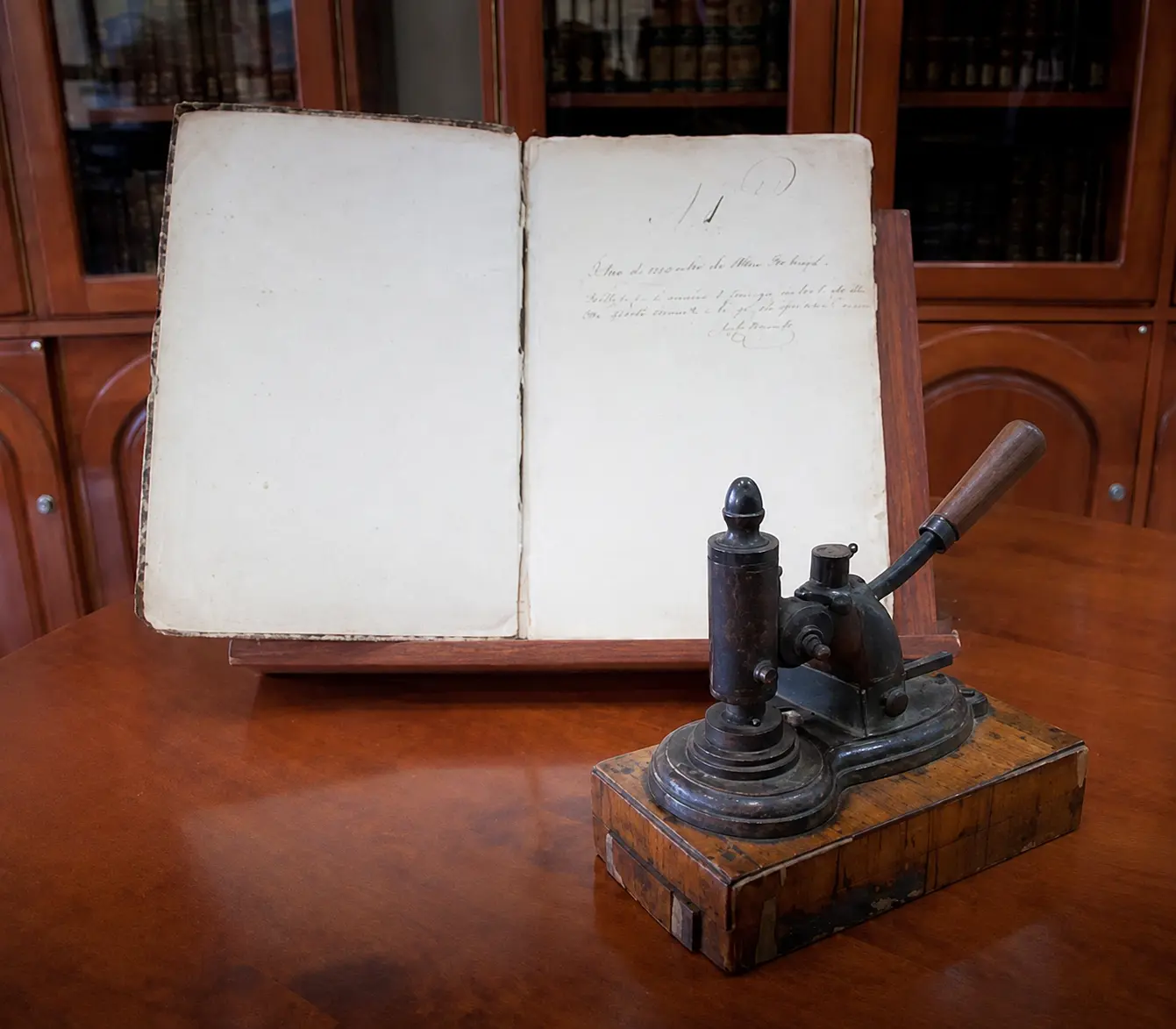 Libro histórico abierto junto a una antigua prensa de sello